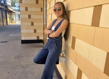 Smiling K–12 math tutor leaning against a brick wall, representing personalized academic support and student success.