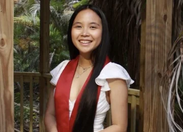 Qualified K–12 math tutor standing outdoors in a park wearing a graduation sash, reflecting her educational background and passion for teaching.